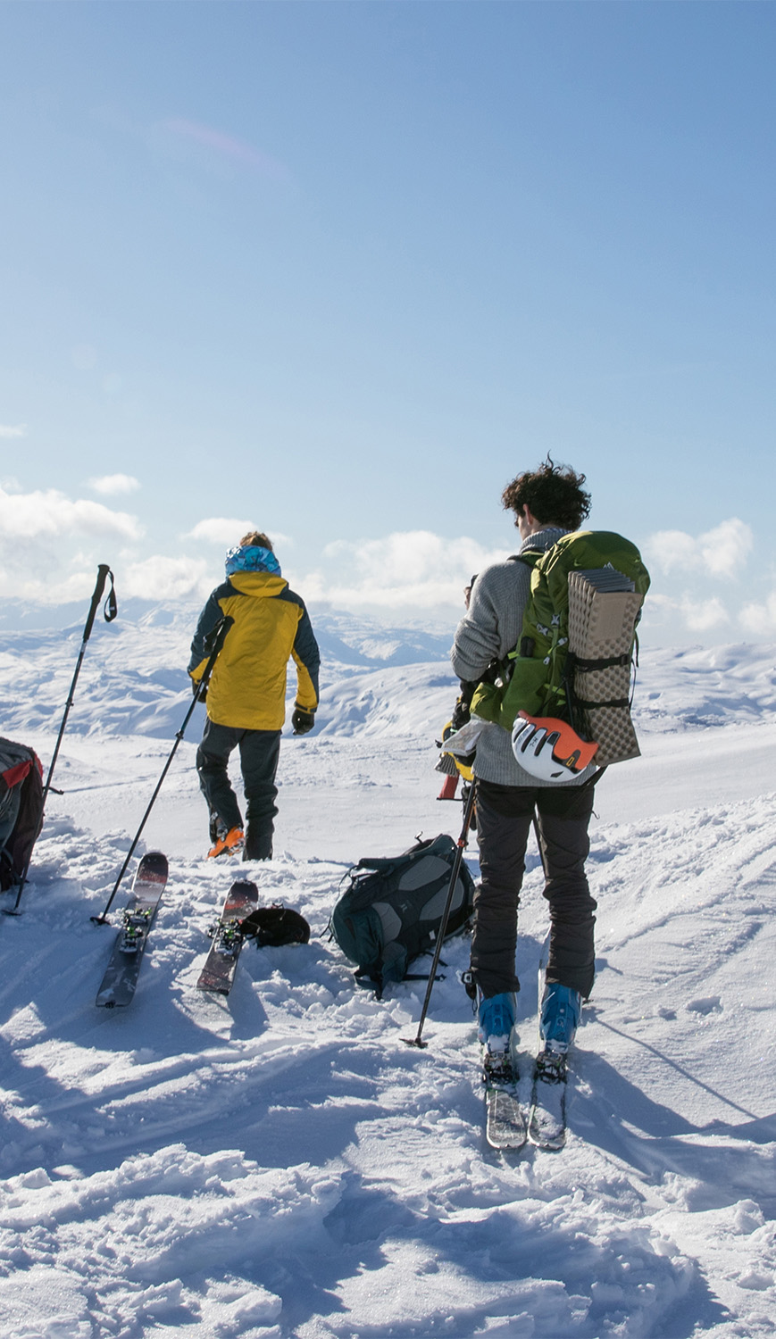 Tre skigåere titter ned en bakke